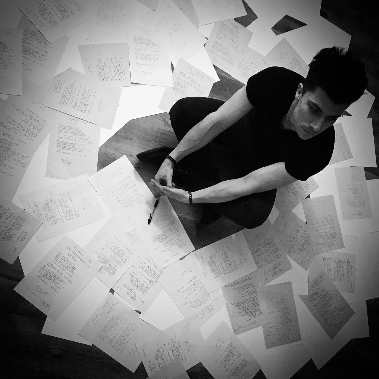 Overhead shot of Ben Christo surrounded by over 70 handwritten lyric sheets spread across the floor